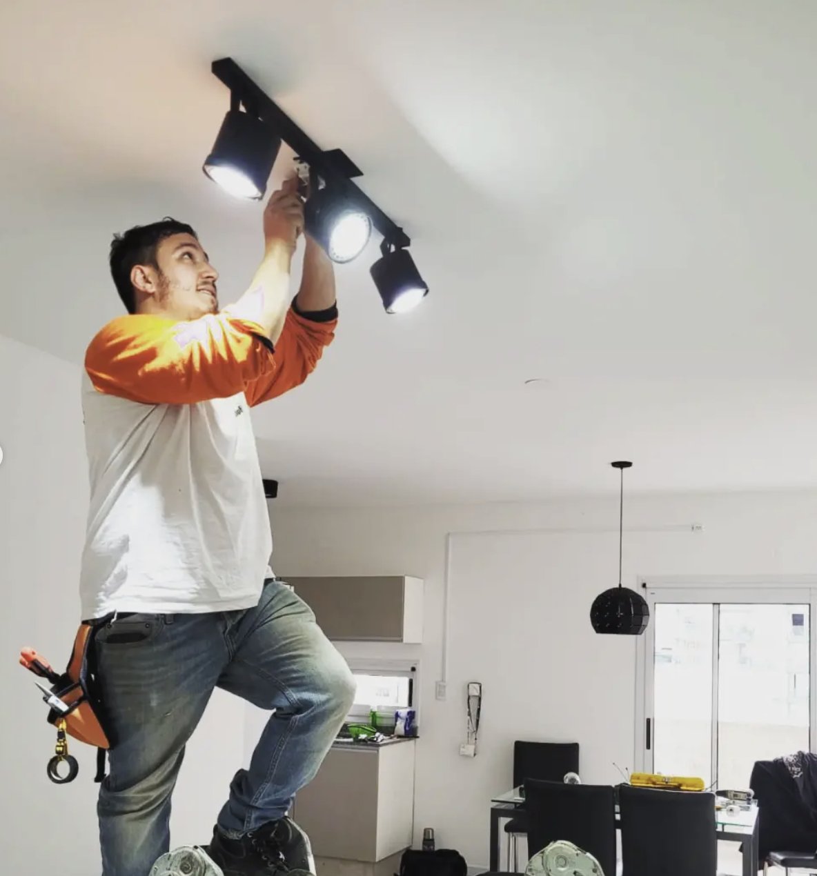 Bruno Cabrera instalando artefactos de iluminación en el techo de una vivienda